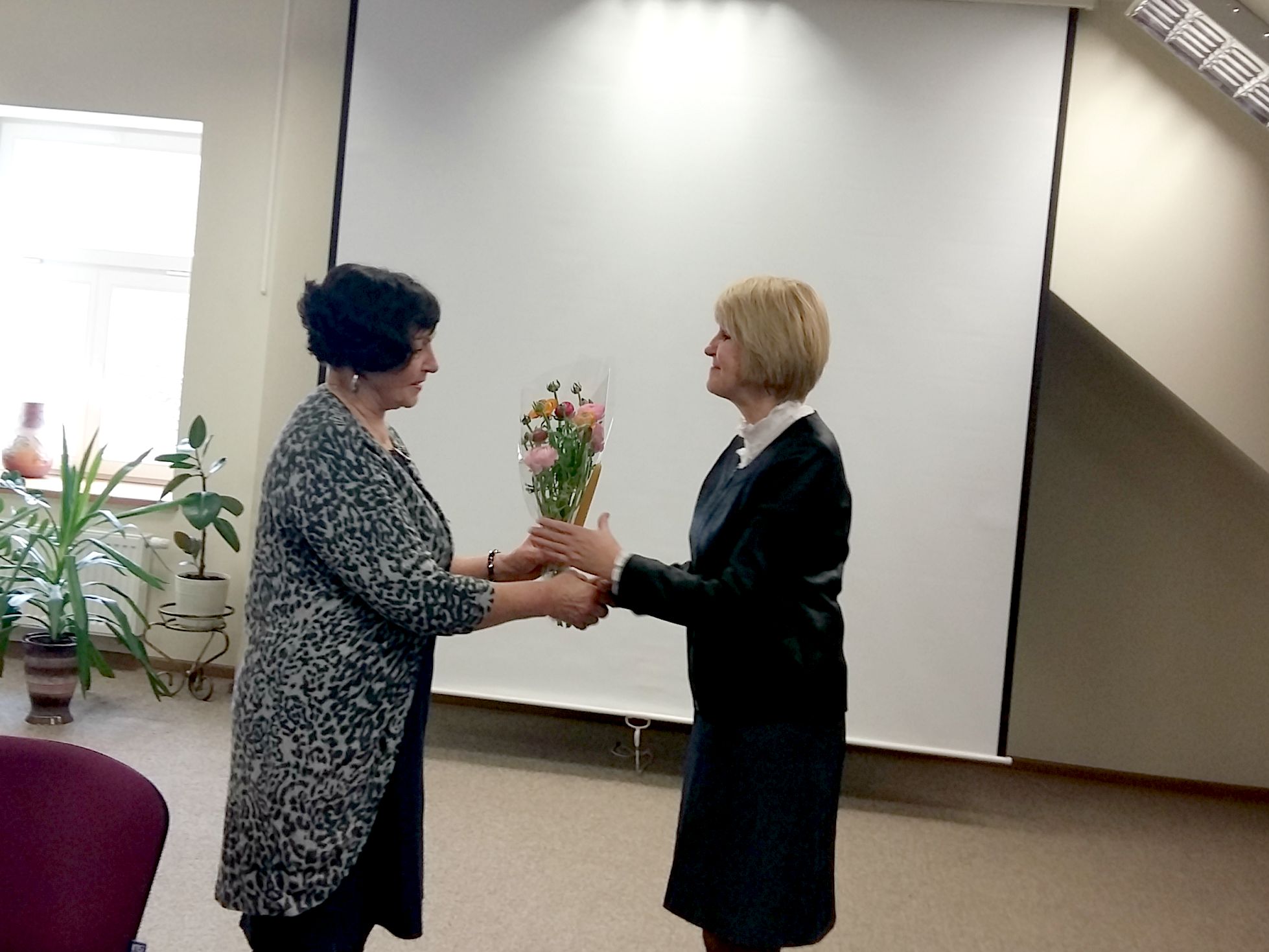 Dalia Poškienei nuskambėjo nuoširdus kraštiečių sveikinimas gimtadienio proga. M. Daukšos viešosios bibliotekos vadovė Virginija Grigorjevienė (dešinėje) viešniai įteikė gėlių. A. Balčiūnienės nuotr. 